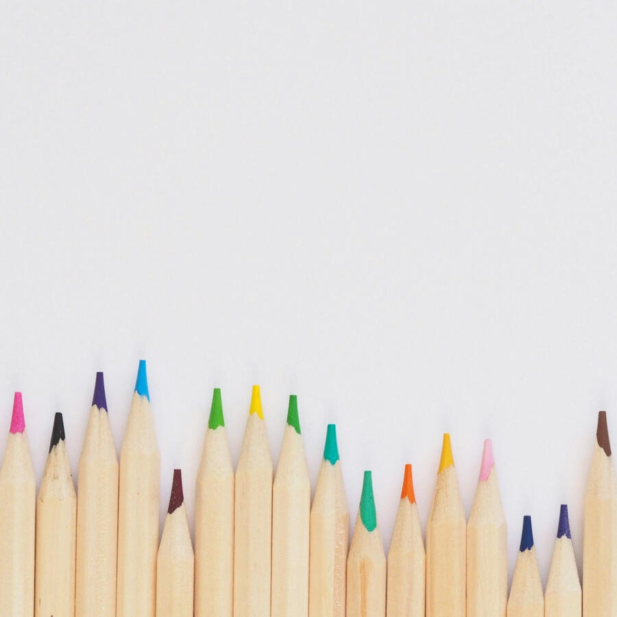 Lined-up colored pencils against a white background