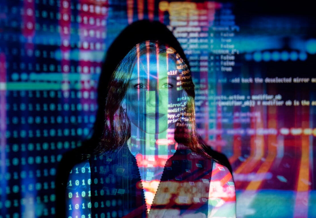 Girl standing in front of colorful projection of lines of code